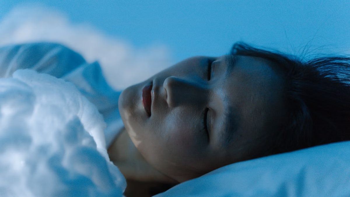 A tranquil scene of a woman sleeping comfortably on a white pillow, evoking peace.
